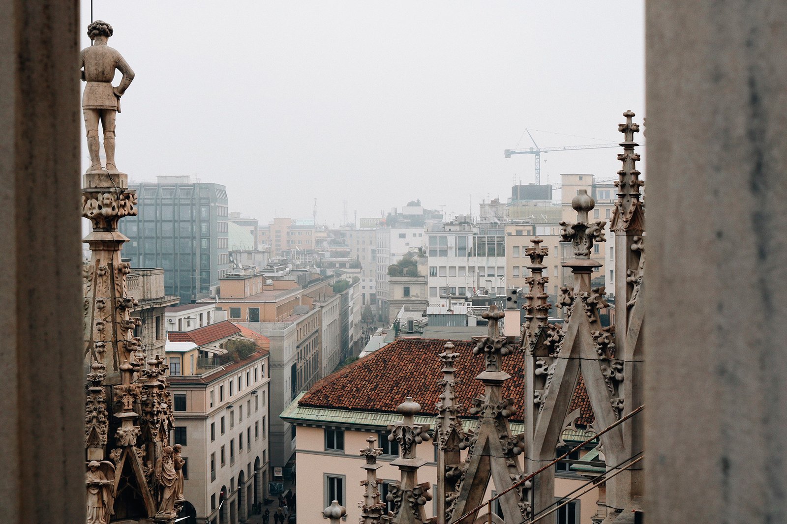 Estátua, detalhes da Duomo e Milão ao fundo