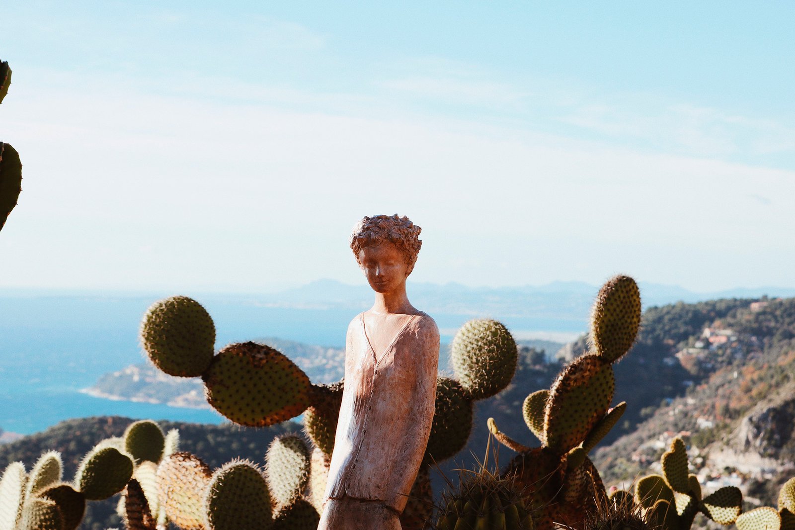 Escultura, cactus e a costa azul ao fundo